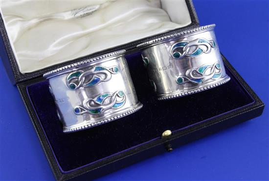 A cased pair of Edwardian Art Nouveau silver and enamel napkin rings by William Hair Haseler, gross 3 oz.